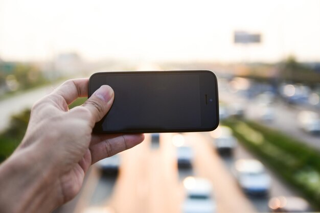 Foto close-up di una mano tagliata usando uno smartphone sulla strada