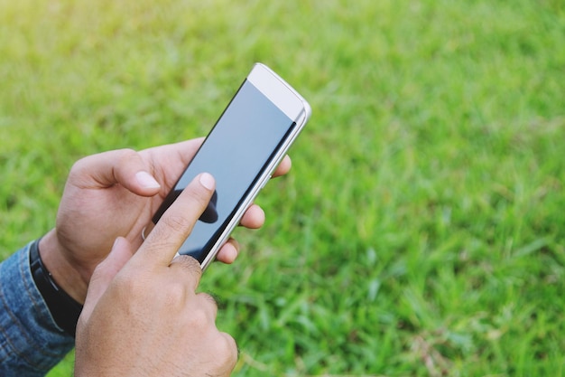 close-up of cropped hands using phone on land