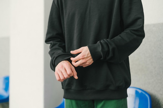 Photo close up cropped photo man in black sweatshirt and green pants focus on hands hands of a stylish man in casual clothes background copy space