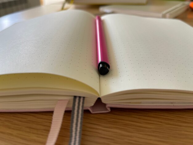 Close up cropped shot of a notebook with pink pencil between pages