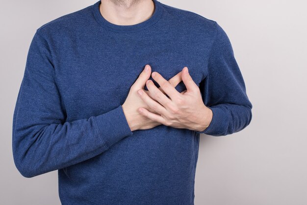 Close-up cropped view photo portrait of unhappy frightened guy holding hands on chest wearing blue pullover isolated grey background