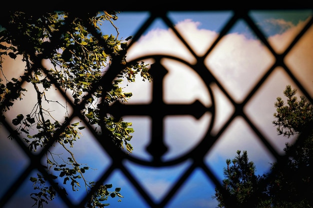 Photo close-up of cross on metal grate against sky