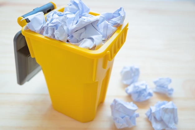 Photo close-up of crumpled paper in garbage bin on floor