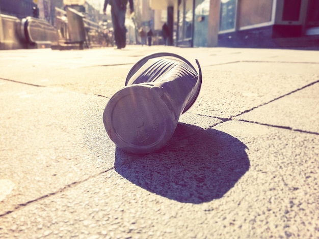 Close-up of crushed drink can on footpath in city