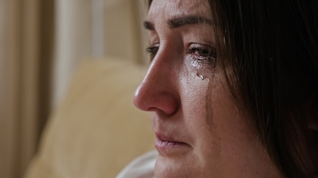 Close-up of a crying young woman with blurry mascara dripping down her cheeks