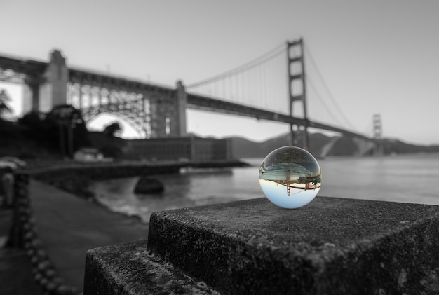 Photo close-up of crystal ball on bridge over river against sky