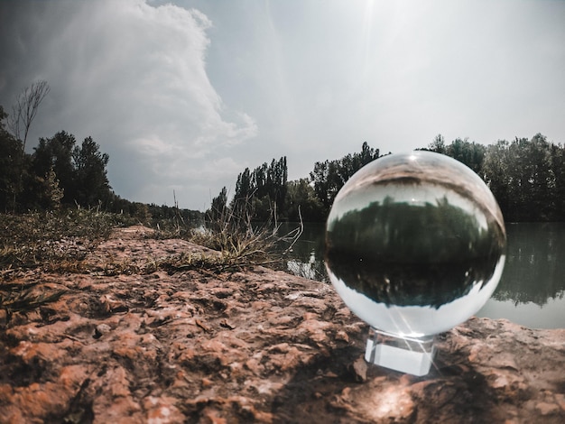 Close-up of crystal ball on field against trees
