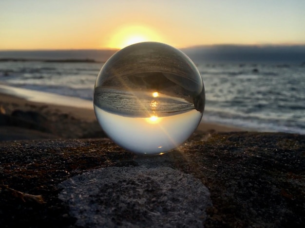 close-up of crystal ball on sand at beach during sunset