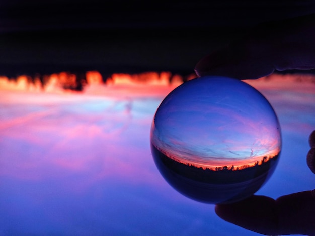 Foto close-up di una palla di cristallo sull'acqua contro il cielo durante il tramonto