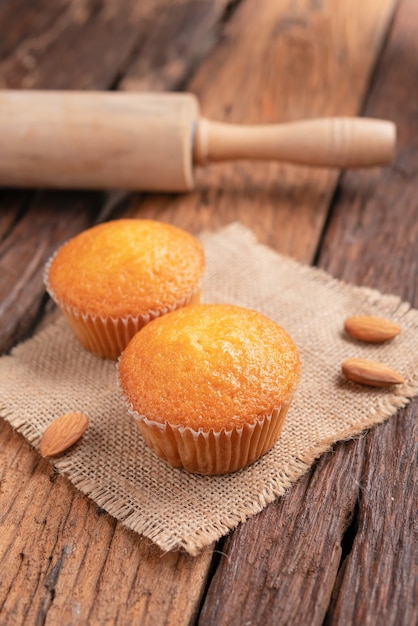 Close up a cup of almond cake against sack fabric on wooden table
