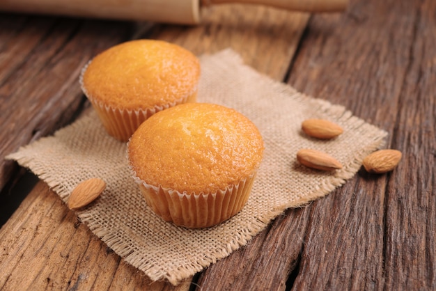 Close up a cup of almond cake against sack fabric on wooden table