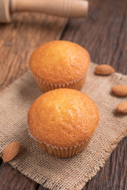 Close up a cup of almond cake against sack fabric on wooden table