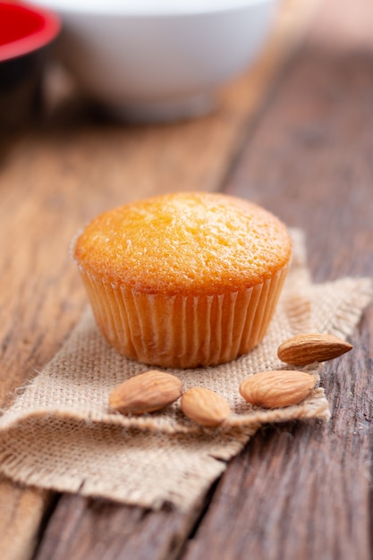 Close up a cup of almond cake against sack fabric on wooden table