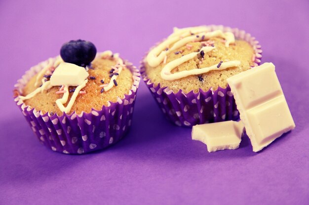 Close-up of cup cakes over purple background