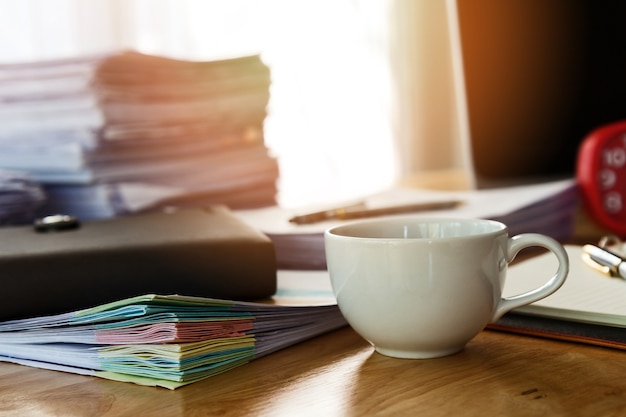 Close up of a cup of coffee and office supplies on desk in office at morning