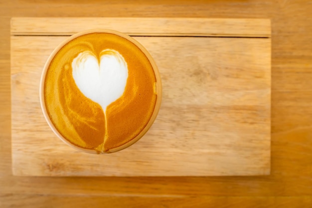 Close up cup of coffee with Cappuccino or latte art milk foam surface on wooden table Image top of view