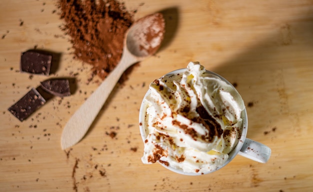 Close-up of a cup of coffee with cocoa powder, cinnamon and chocolate whipped cream
