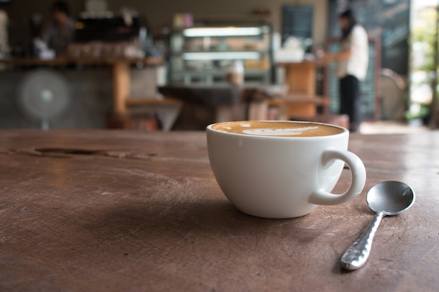 Закройте чашку горячего латте арт-кофе на деревянном столе