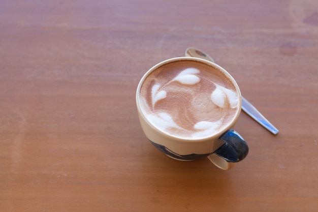 Закройте чашку горячего кофе латте Арт на деревянный стол.