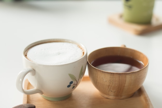 Закройте чашку горячего латте-кофе на белом столе