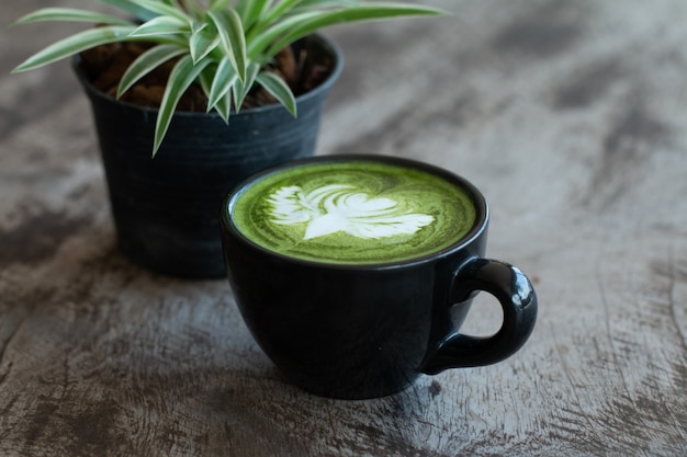 Foto primo piano di una tazza di tè verde matcha bevanda calda di arte tardiva sul tavolo di legno