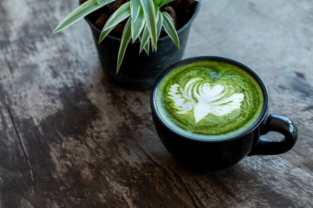 Close up a cup of Matcha green tea Late art hot drink on wooden table