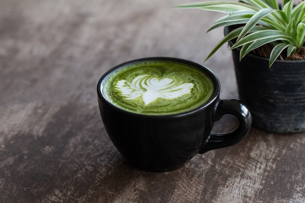 Foto chiuda su una tazza del latte del tè verde di matcha sul fondo di legno della tavola