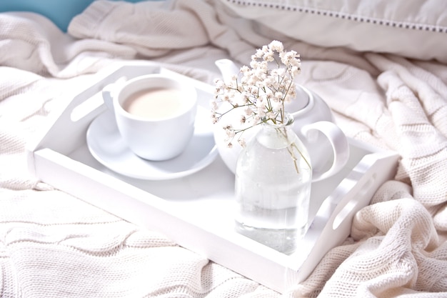 Close up of cup of tea, milk, teapot and bouquet 