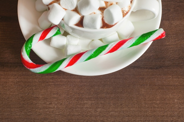 Foto primo piano della tazza con cioccolata calda, marshmallow e bastoncino di zucchero