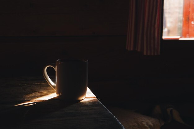 Photo close-up of cup on wooden table in darkroom