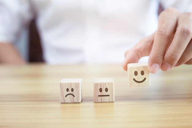 Close up customer hand choose smiley face and blurred sad face\
on wood cube