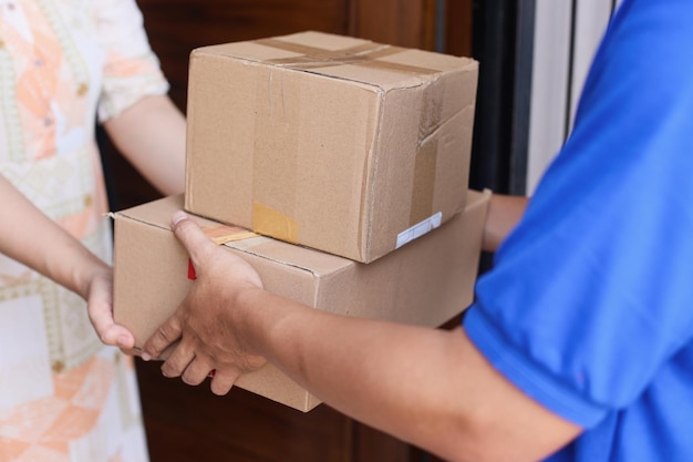 Close-up of customer receiving parcel box from delivery man - courier service concept.