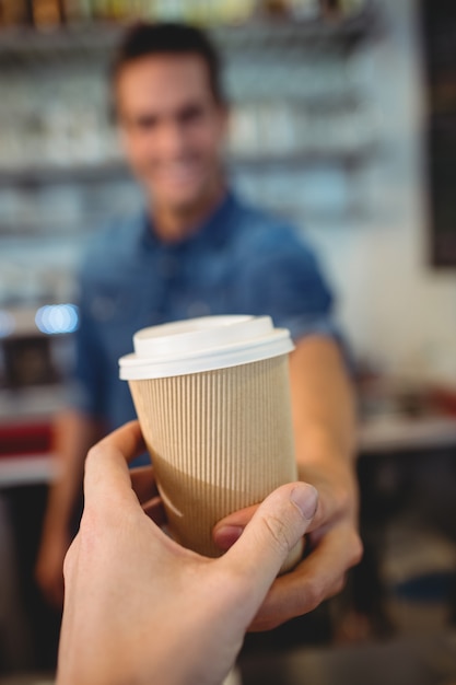 Foto primo piano del cliente che prende caffè dal barista al caffè