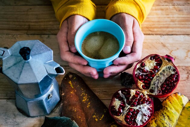 Photo close up of cut out person doing breakfast at home with coffee and fruit pommegranate in autumn decoration leaves colors concept healthy food lifestyle wooden table moka cafe people unrecognizable