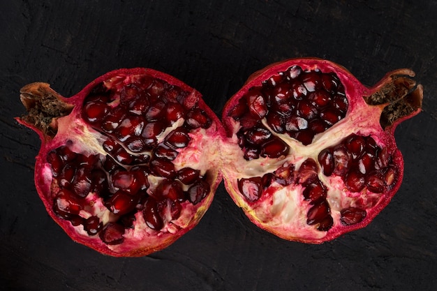 Close up of cut pomegranate on black background, fresh garnet