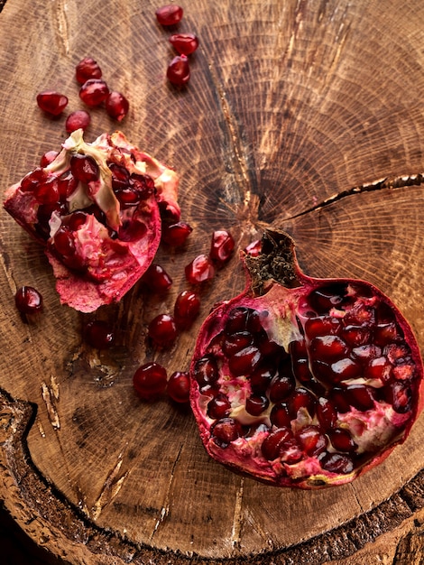 Close up of cut pomegranate on wooden board, fresh garnet background