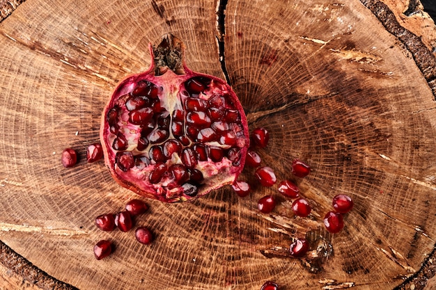 Close up of cut pomegranate on wooden board, fresh garnet background