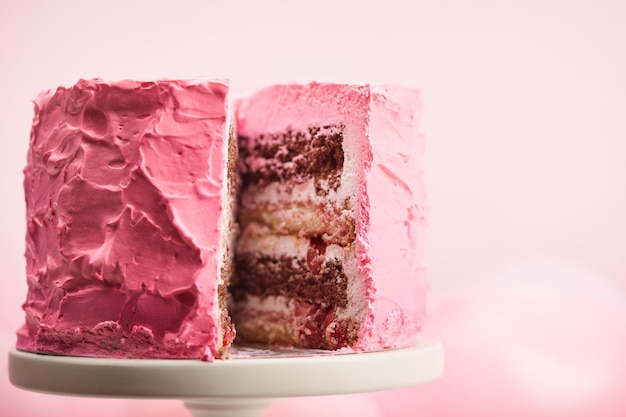 Foto chiuda in su della torta di compleanno dolce tagliata sul basamento della torta sul rosa