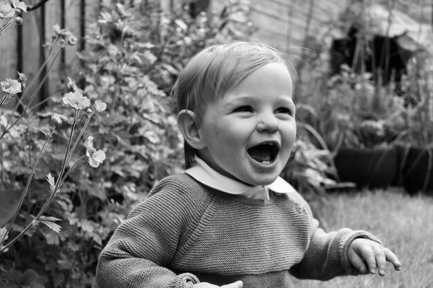 Photo close-up of cute baby boy with mouth open in yard