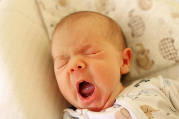 Close-up of cute baby girl yawning on bed