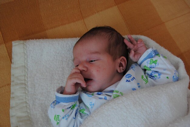 Close-up of cute baby lying on bed at home