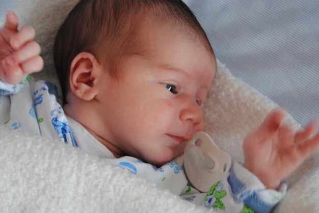 Close-up of cute baby lying on bed at home