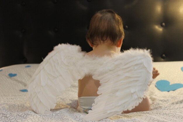 Photo close-up of cute baby with wings at home