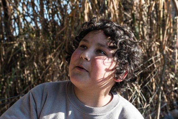 Close-up of cute boy looking away against plants