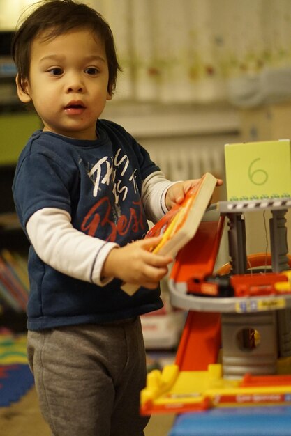 Close-up of cute boy with book standing at home