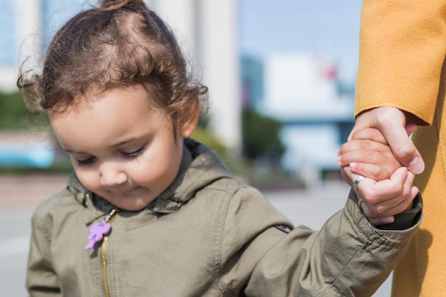 Photo close-up of cute daughter holding mother hand in city