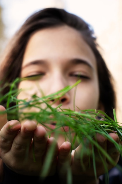 Foto close-up di una ragazza carina che soffia l'erba