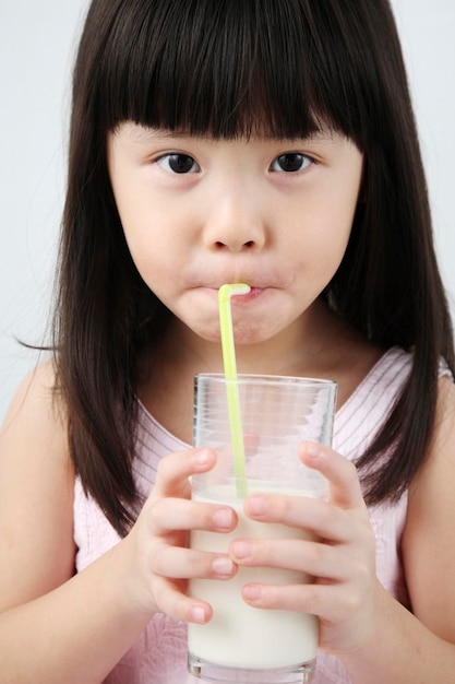 Close-up cute girl drinking milk glass against white background