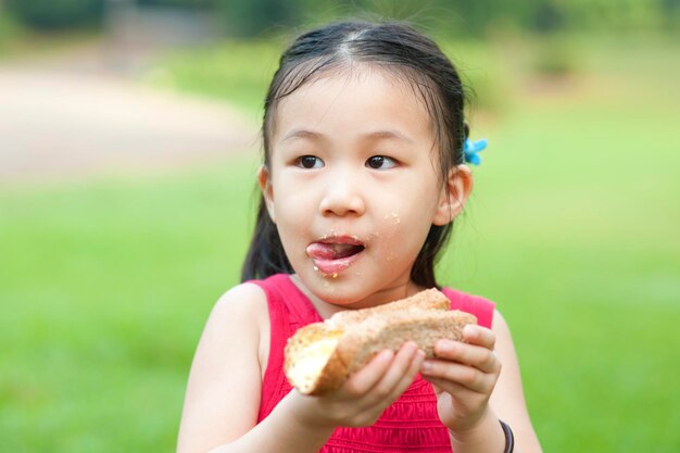 Close-up of cute girl eating bread while standing park