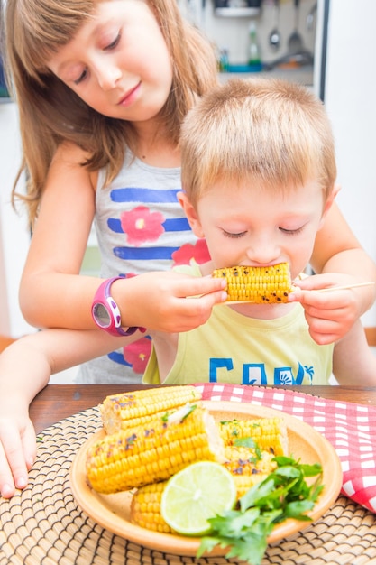 Foto close-up di una ragazza carina che dà da mangiare al fratello sul tavolo a casa